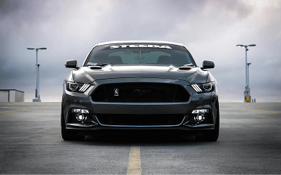 A dark sports car parked under a cloudy sky