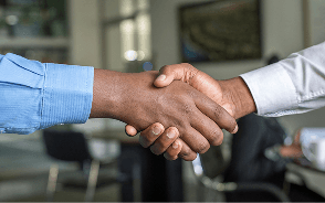 Two people shaking hands across a desk