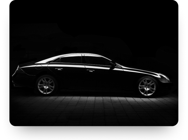 A black saloon car lit from the side in a dark studio