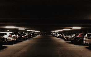 Rows of cars parked in a dimly lit car park