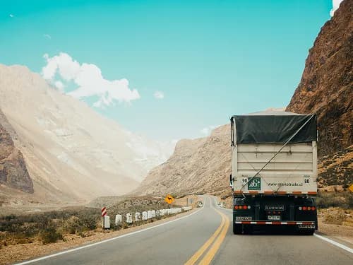 A covered lorry driving along a mountain road