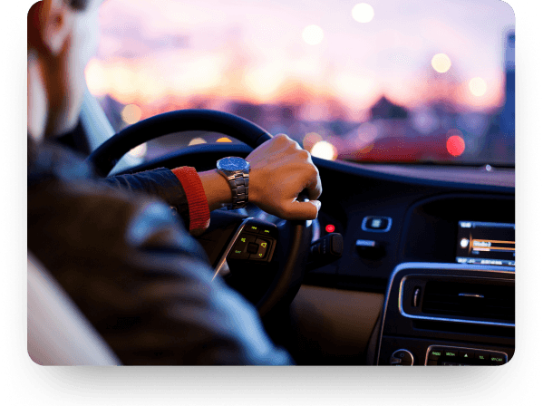 A driver's hands on the steering wheel at dusk