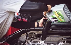 A mechanic pouring oil into an engine