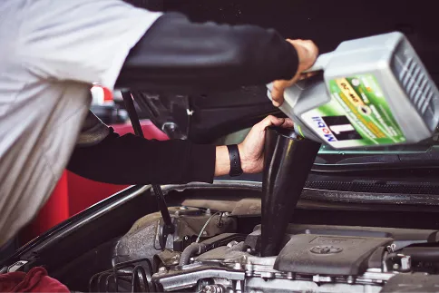 A mechanic pouring oil into an engine