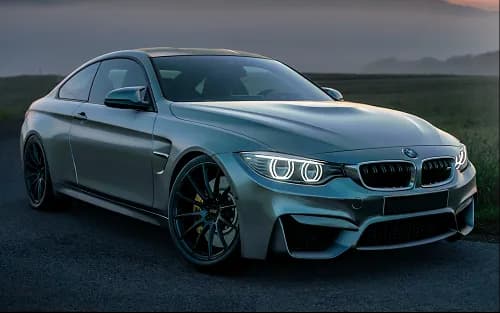 A grey sports saloon parked outside at dusk
